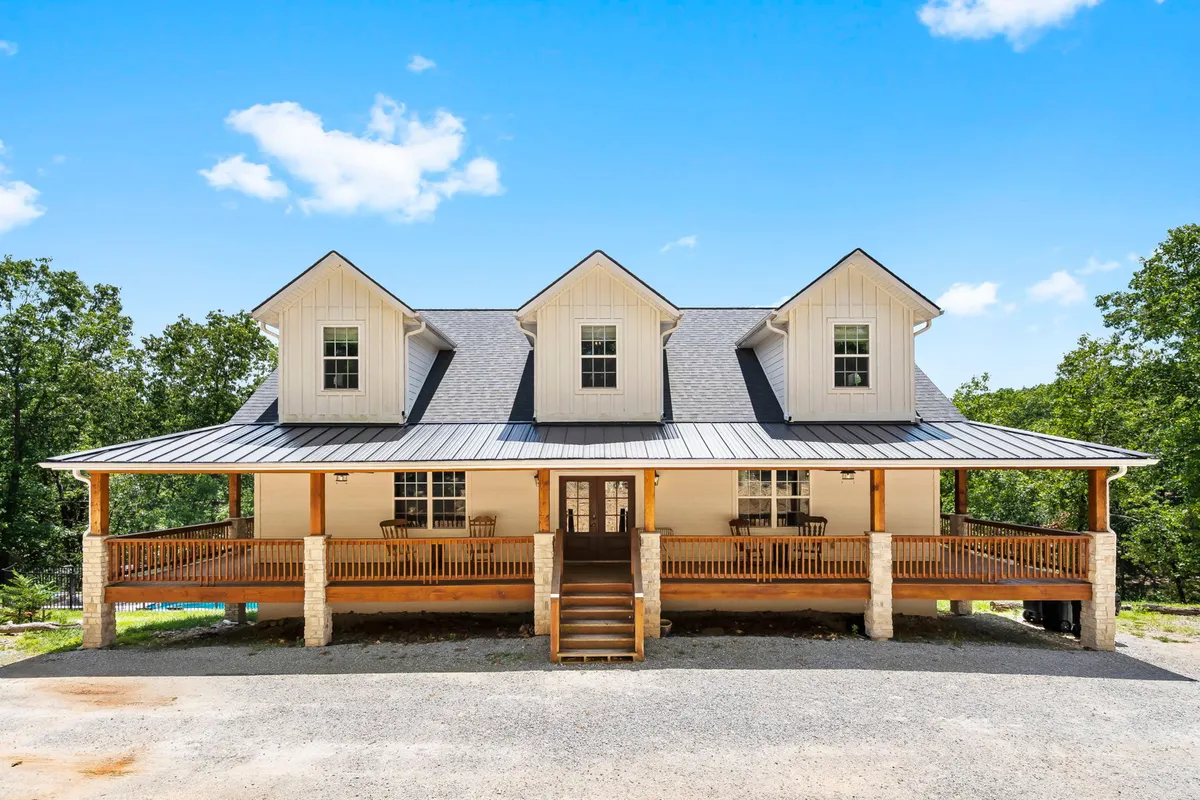 This image features the home's wide, welcoming front porch with inviting seating, the front door, and a charming gabled roof. The porch suggests a communal area perfect for morning coffee, reading, or unwinding outdoors.