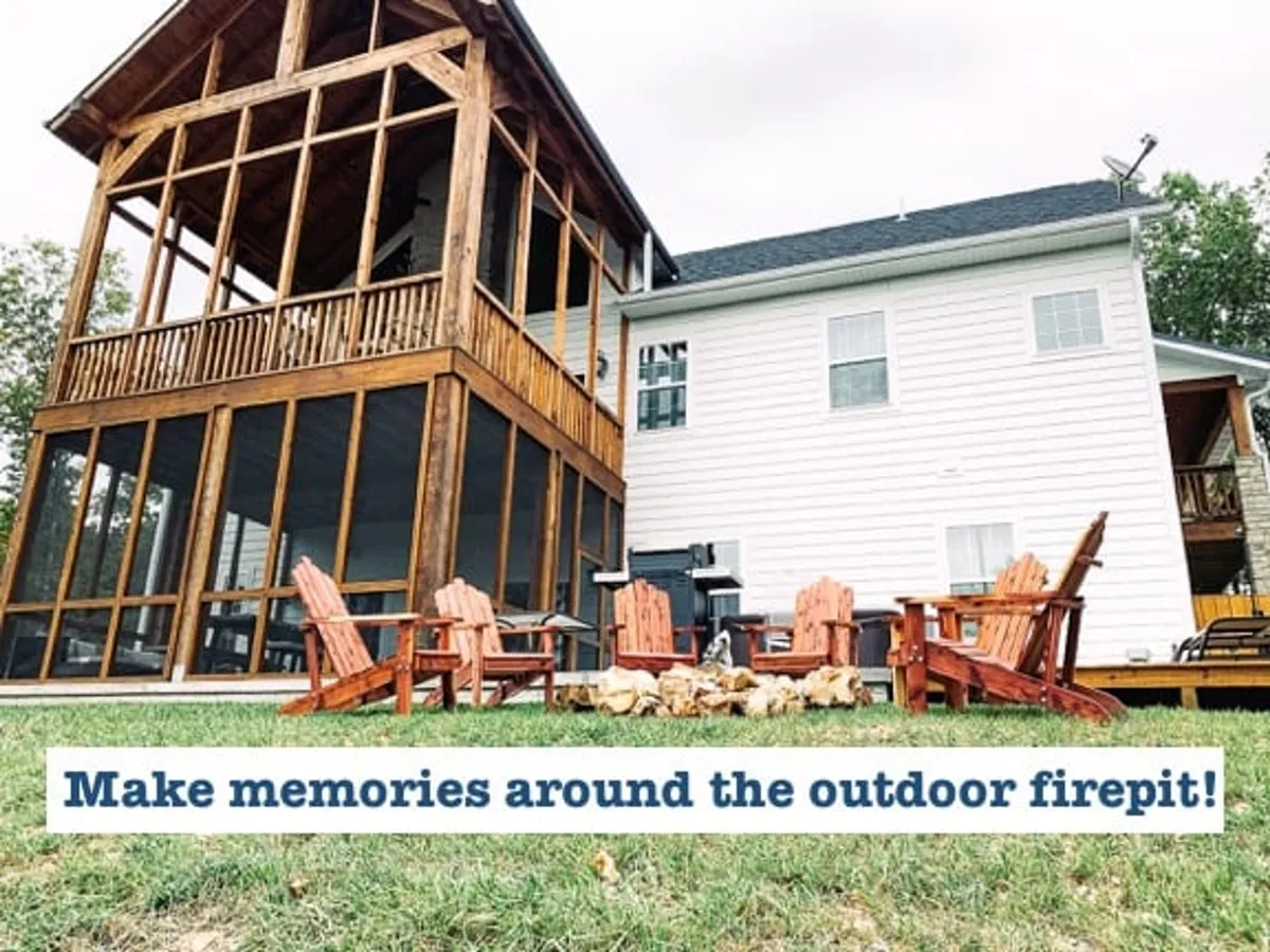A cozy firepit area with Adirondack chairs gathered around a glowing fire, adjacent to a screened porch. The scene invites group storytelling, marshmallow roasting, and stargazing under the night sky.