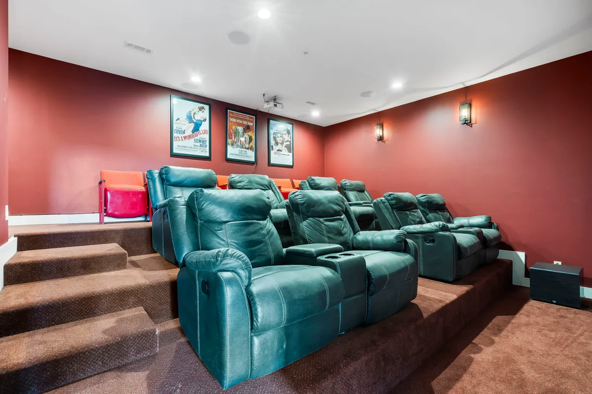 A cozy, purpose-built home theater with reclining seats, movie posters, and ambient lighting, designed for immersive movie nights and shared entertainment.