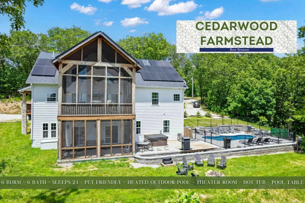 A vibrant outdoor scene featuring a large swimming pool surrounded by lounge chairs, a screened porch, and expansive greenery. The area is set up for both daytime swimming and evening gatherings, with views of a hot tub and fire pit seating visible.