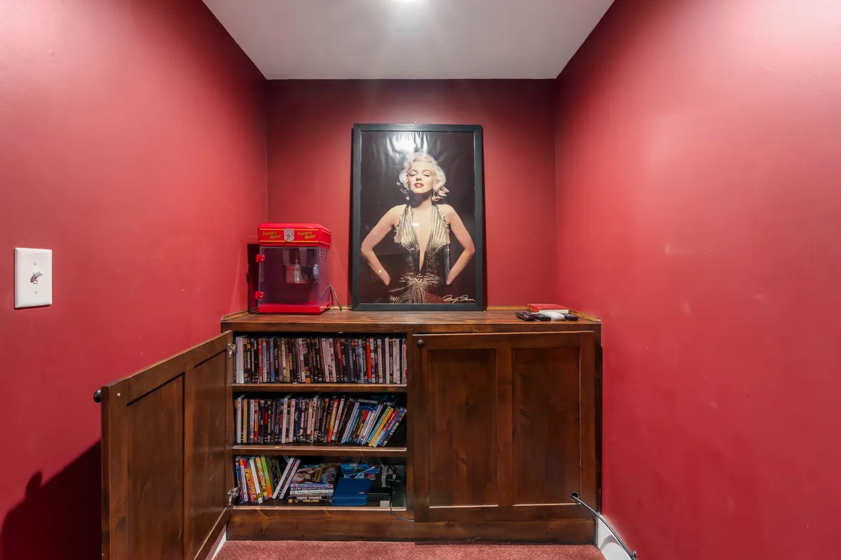 A nostalgic nod to classic entertainment, featuring a Marilyn Monroe poster, a vintage-style popcorn machine, and a shelf brimming with DVDs, creating a playful, cinematic vibe.