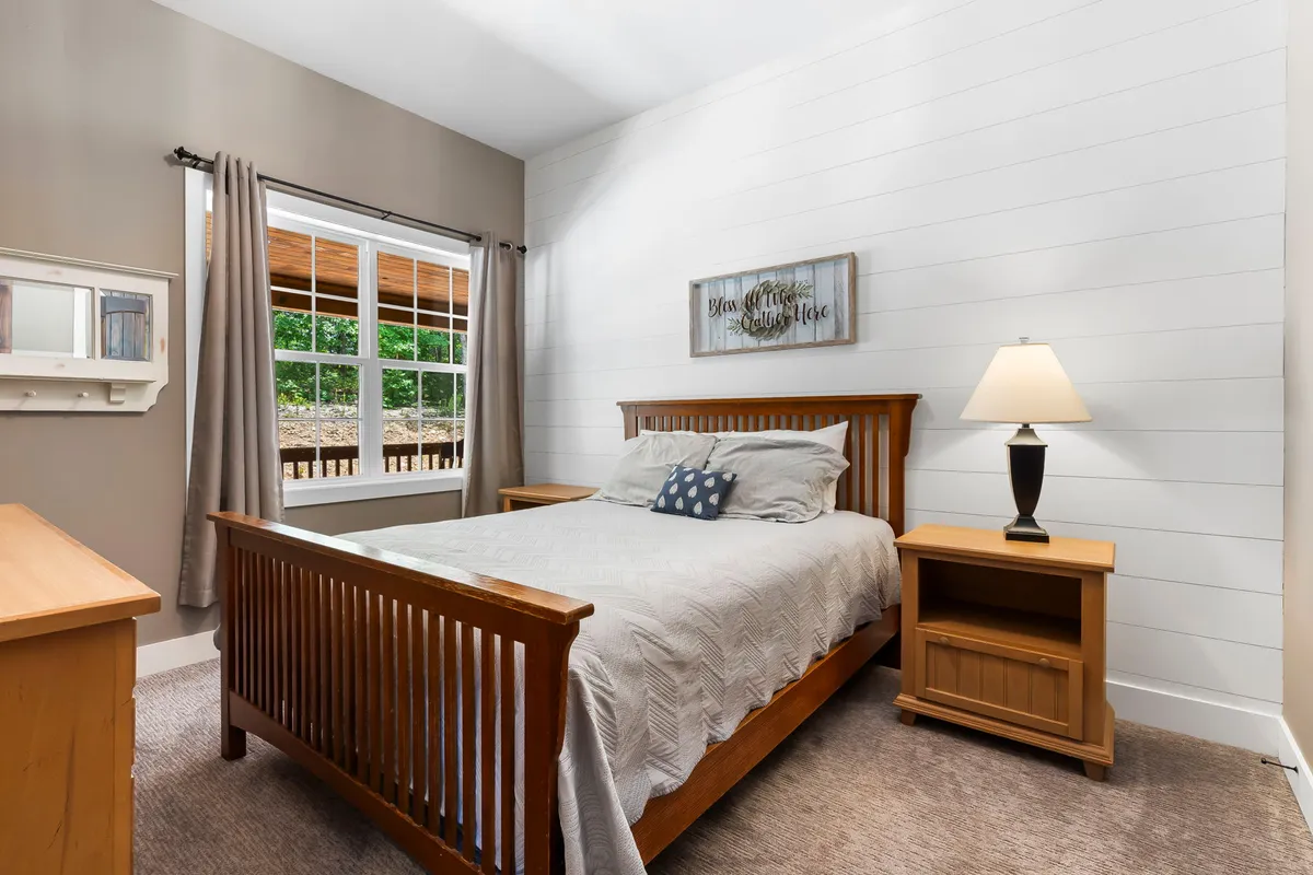 A serene bedroom featuring a comfortable bed, soft blue-striped bedding, a large window allowing natural light to gently fill the space, nightstands with lamps, and decorative wall art. The room exudes peace and is perfect for restful nights and rejuvenating mornings.